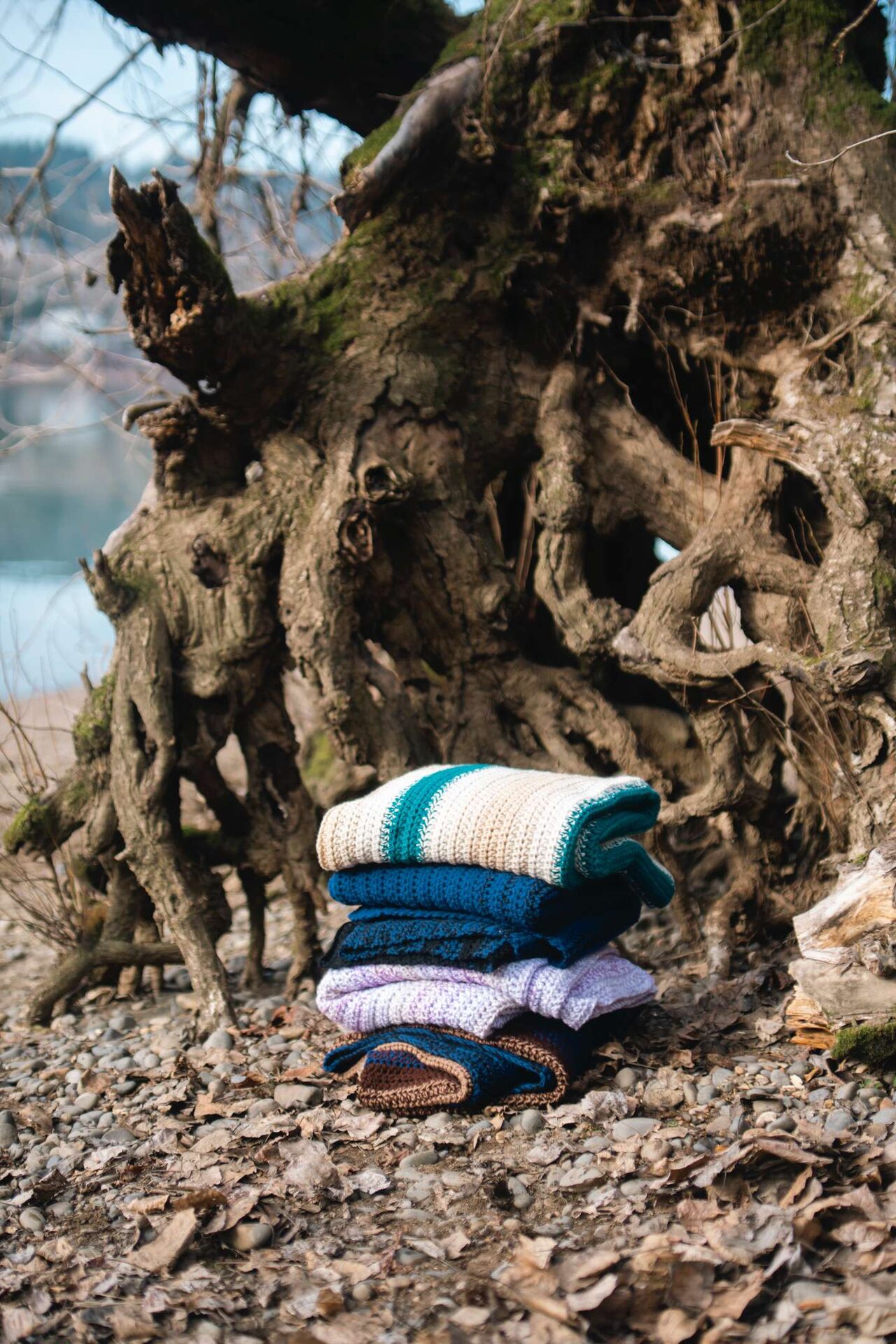 Stack of hand-crocheted blankets among coastal tree roots